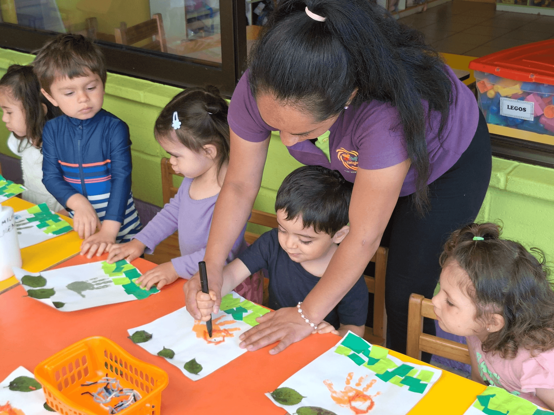 Educadora NATGIO guiando a los niños en actividades de pintura y expresión artística